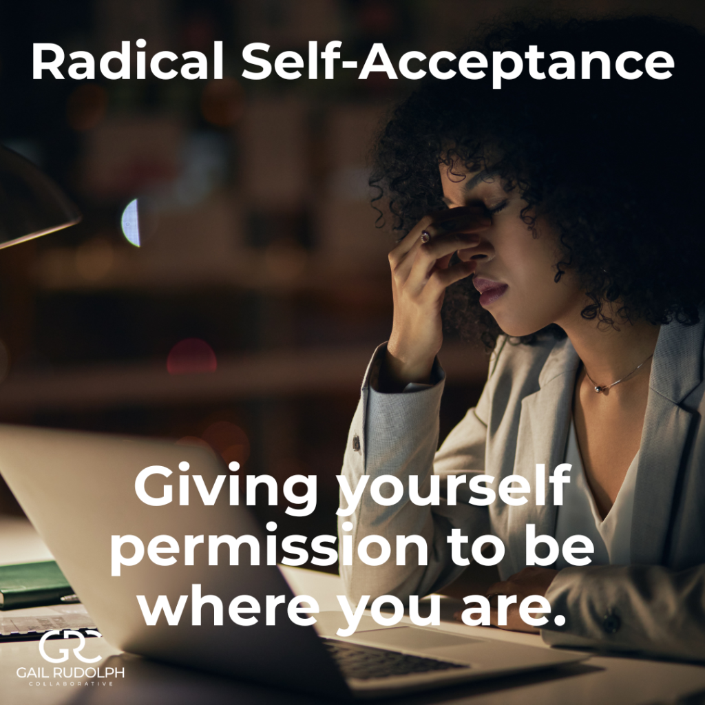 Women sitting in front of laptop pinching the bridge of her nose, looking tired.